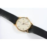 A GOLD WRISTWATCH BY OMEGA the signed circular dial with Arabic and dot numerals, on a black leather