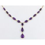 AN AMETHYST AND GOLD DROP NECKLACE formed with graduated oval-shaped cabochon amethysts,