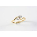 A DIAMOND TWO STONE CROSS-OVER RING set with two circular old-cut diamonds, in 18ct gold. Size T