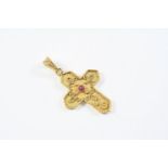 A GOLD CRUCIFORM PENDANT mounted with a circular cabachon ruby and with rope and ball decoration,