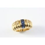 A SAPPHIRE AND GOLD RING the 18ct gold graduated ridged mount is set with six calibre-cut sapphires.