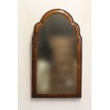 A GEORGE I STYLE WALNUT FRAMED WALL MIRROR. With an arched plate within a curved and moulded walnut