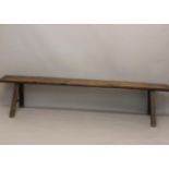 A 19TH CENTURY OAK LONG BENCH. With a long single plank top on twin 'A' frame supports with