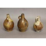 TWO BELLARMINE TYPE BOTTLES AND ANOTHER. Two salt glazed stoneware bottles with bearded faces