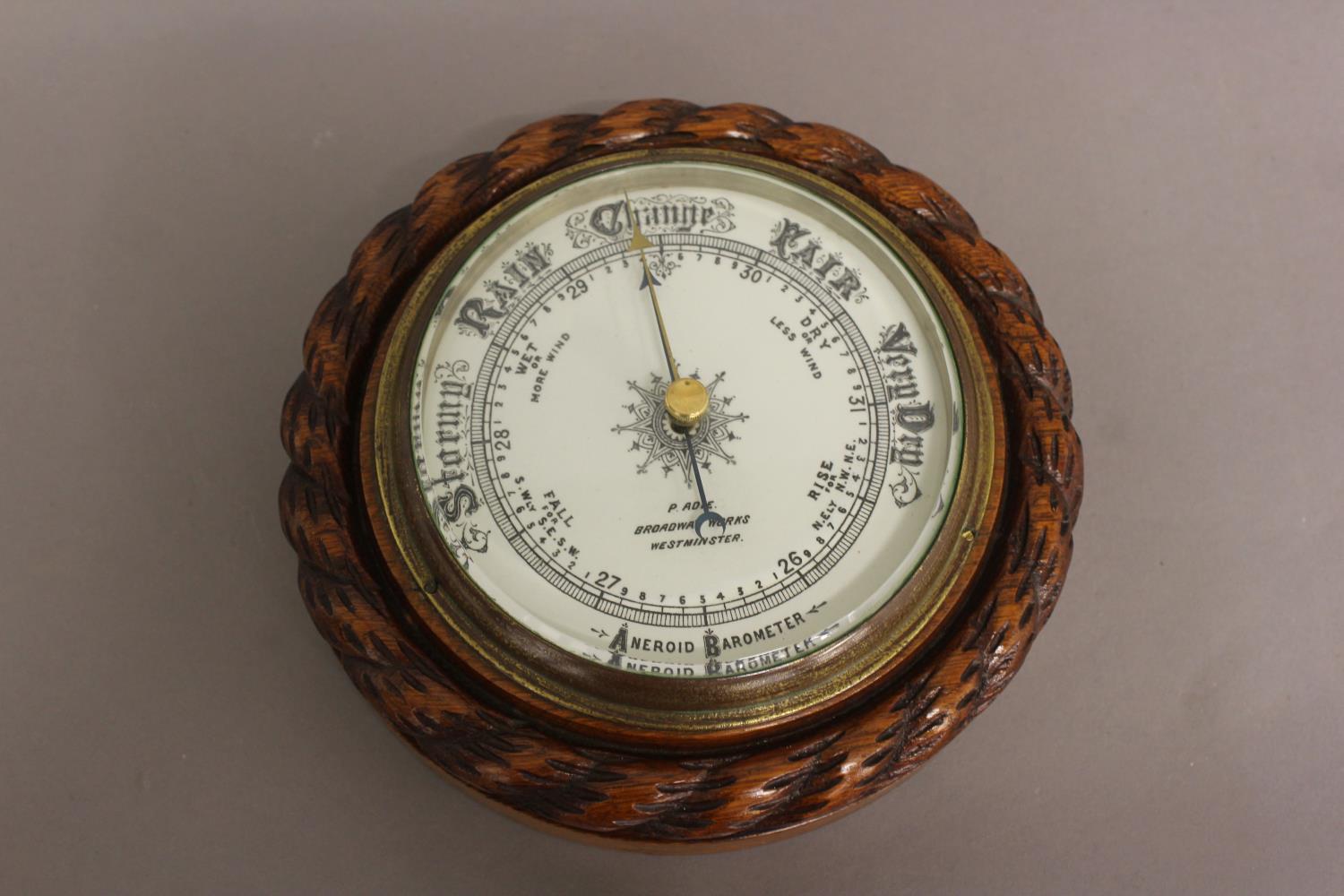 AN OAK FRAMED BAROMETER BY ADIE OF WESTMINSTER. With a carved 'rope twist' surround and decorative