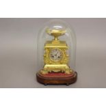 A REGENCY GILT BRASS MANTLE CLOCK AND GLASS DOME. The clock with a silvered dial with engine