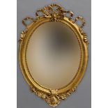 A VICTORIAN GILT FRAMED OVAL WALL MIRROR. With a bevel edged oval mirror plate within a beaded and