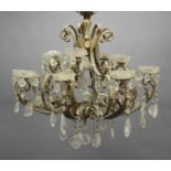 A GILT BRASS CHANDELIER the ten scrolling branches each for two lights and hung with prismatic
