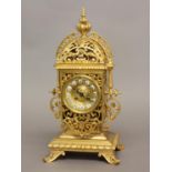 A VICTORIAN GILT BRASS MANTEL CLOCK. The elaborate pierced scrolling case containing a central