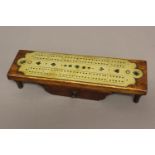 A LATE VICTORIAN OAK AND BRASS CRIBBAGE BOARD. The rectangular oak top mounted with a brass cribbage