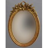 A VICTORIAN GILT FRAMED OVAL WALL MIRROR. With a bevel edged oval plate within a beaded and