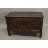 A 17TH CENTURY OAK COFFER. With a rising rectangular top with moulded border, above a three panel