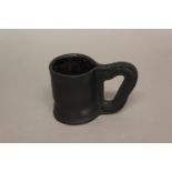 A 17TH CENTURY STYLE SEWN LEATHER MUG. A black leather sewn mug of traditional construction, late