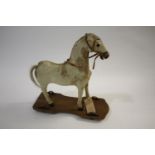 19THC PULL ALONG HORSE a small pony skin horse, mounted on a pine base and with metal wheels to each