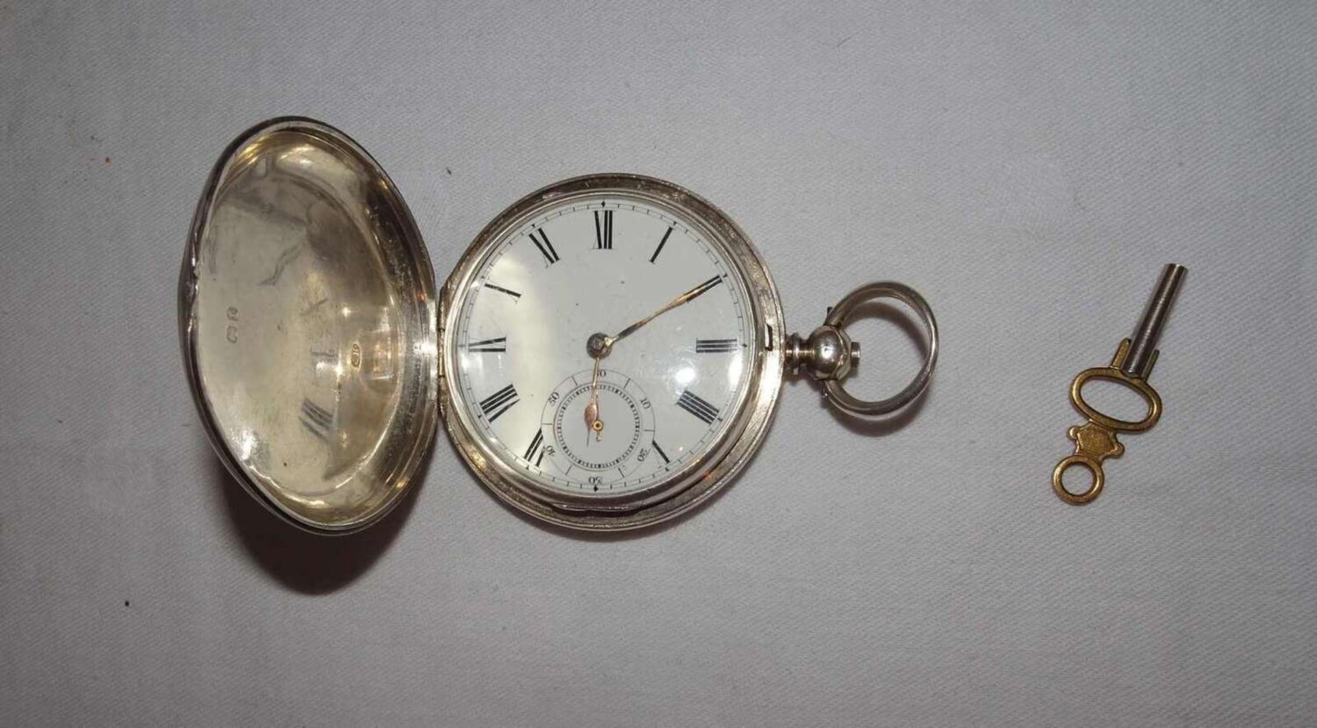 silberne Taschenuhr mit aufklappbarem Gehäuse. Schlüsselaufzug / Schlüssel dabei. Uhr läuft an.