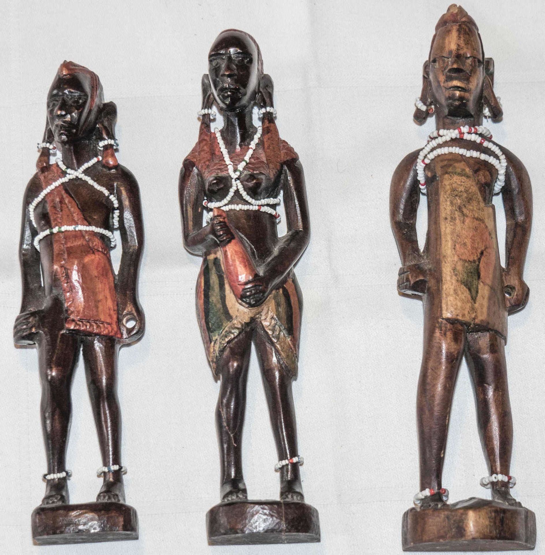 Drei Holzfiguren, Afrika, mit Kettenbehang.Three wooden figures, Africa, with chain hangings.