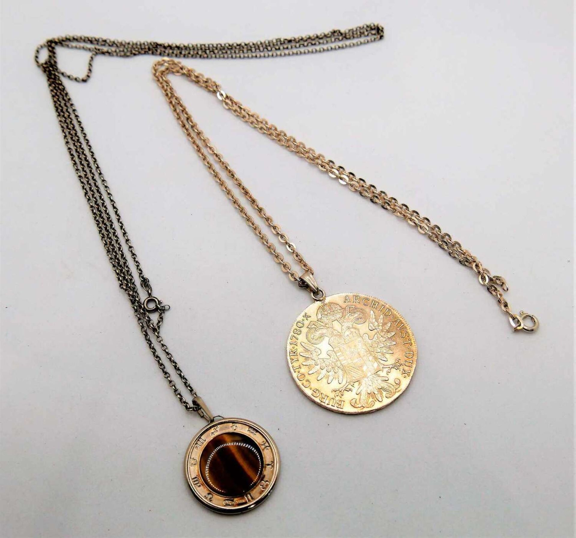 1 Maria Theresienthaler an 835er Silberkette, sowie 1 Medaille "Gemini" mit Tigerauge an 835er