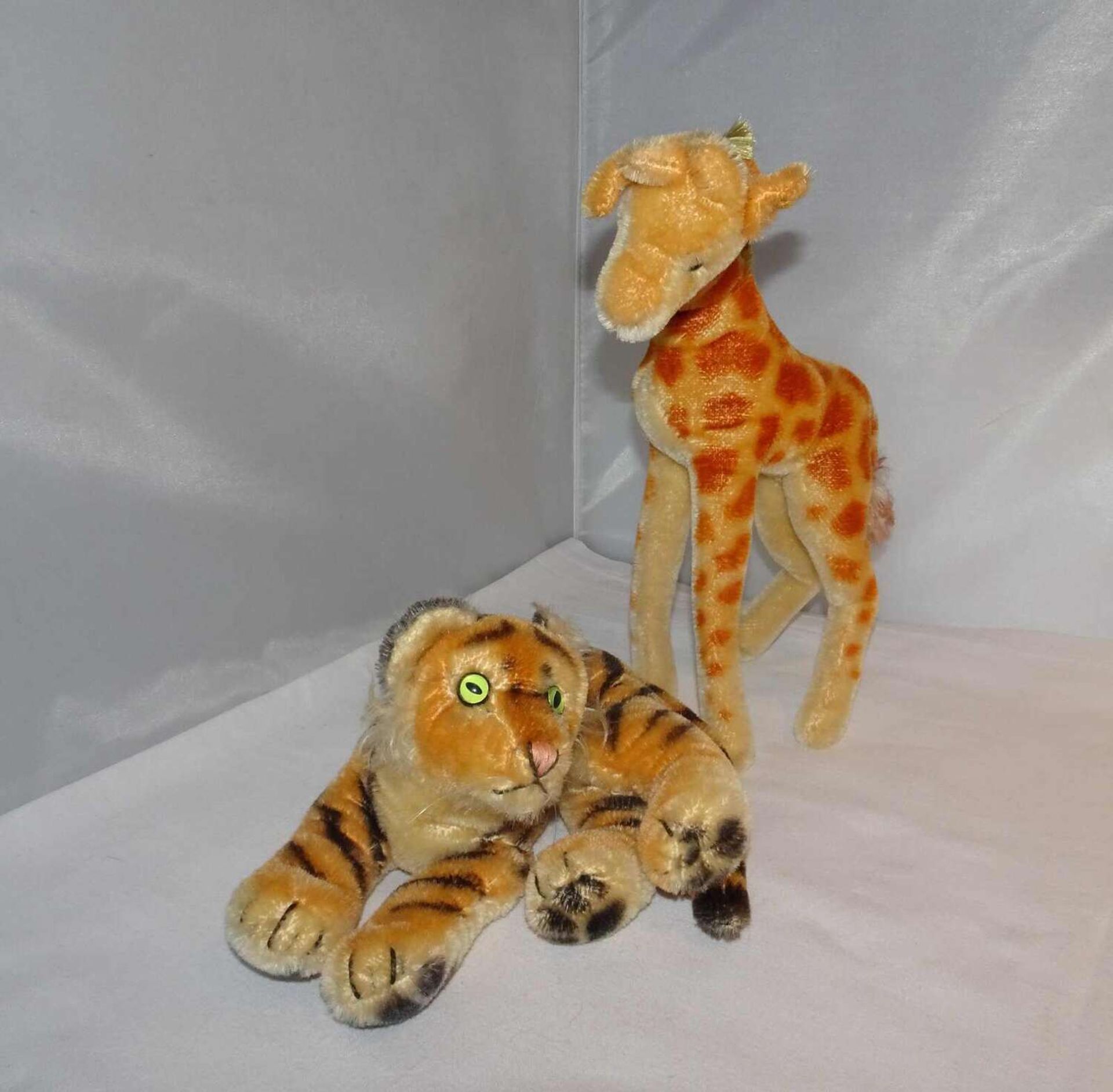 2 Steifftiere, ca. 60er Jahre, 1x Tiger mit Knopf, sowie 1x Giraffe mit Knopf und Fahne. 2 Steiff