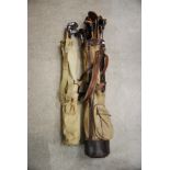 TWO VINTAGE CANVAS AND LEATHER TRIMMED GOLF BAGS CONTAINING ASSORTED HICKORY SHAFTED AND OTHER