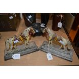 PAIR OF COLD PAINTED CAST IRON DOORSTOPS IN THE FORM OF HORSES WITH COLOURFUL SADDLES