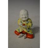 CHINESE PORCELAIN FIGURE OF A SEATED FIGURE HOLDING A FRUIT WEARING A YELLOW COLOURED TUNIC