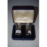 CASED PAIR OF LONDON SILVER SALT POTS WITH EMBOSSED DRAPERY DETAIL AND DETACHABLE SCREW COVERS,