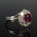 A white metal ruby and diamond cluster ring, circa 1970, centred with a round faceted ruby