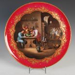 A Vienna porcelain hand-painted circular charger, decorated with a tavern scene after Teniers,