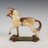 A late 19th century carved wood and painted gesso children's horse pull-toy, with studded leather