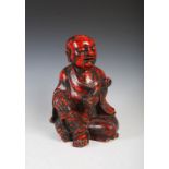 A Chinese carved camphor wood and red lacquered figure of a boy, Qing Dynasty, carved holding a ruyi