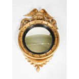 A 19th century giltwood Regency style convex wall mirror, with winged eagle surmount, and ball set
