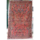 A Persian rug, early 20th century, the madder ground centred with an eight-petalled flower,
