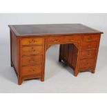 A 19th century Aesthetic Movement walnut pedestal desk, the rectangular top with burgundy coloured