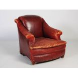 A late 19th/ early 20th century burgundy coloured leather club armchair, with scroll-over back and