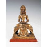 A Chinese gilt bronze figure of Buddha, Qing Dynasty, seated on rectangular stool, mounted on a