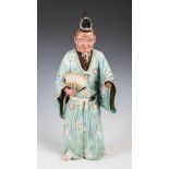 A Japanese pottery figure of a street entertainer, late 19th/ early 20th century, modelled