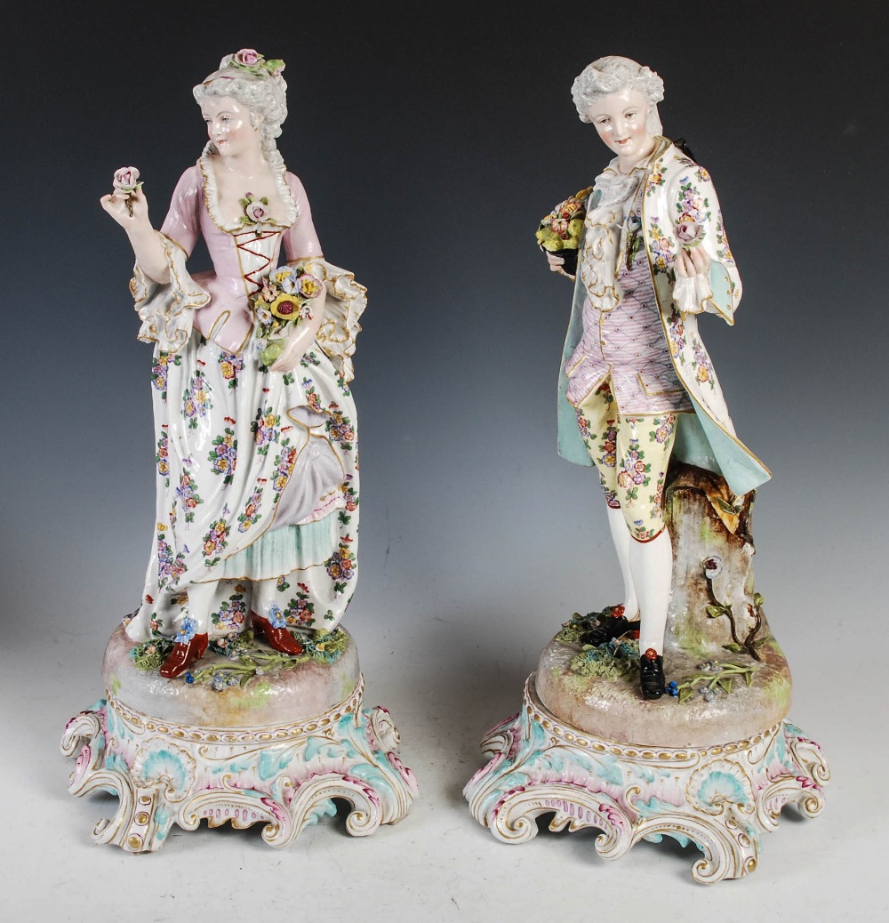 A pair of late 19th century Dresden porcelain figures, the male modelled standing holding a rose