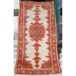 A Persian rug, late 19th/ early 20th century, the off-white ground centred with an oval shaped