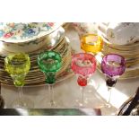 FIVE COLOURED AND CLEAR GLASS CORDIAL GLASSED WITH ENGRAVED VINE DETAIL.