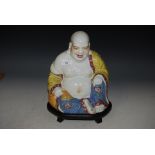 CHINESE PORCELAIN FIGURE OF BUDDHA, WITH POLYCHROME ENAMEL DECORATION ON FOOTED CARVED WOOD STAND.