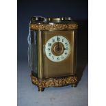 AN EARLY 20TH CENTURY BRASS CASED CARRIAGE CLOCK WITH SERPENTINE OUTLINE, PIERCED SCROLL FRET WORK