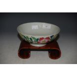 A CHINESE FAMILLE ROSE FOOTED BOWL, DECORATED WITH FLOWERS AND FOLIAGE ON DARKWOOD SCROLL STAND