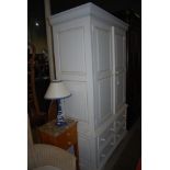 A MODERN PAINTED PINE WARDROBE WITH TWO PANELLED DOORS AND HANGING RAIL TO CUPBOARD ABOVE TWO PAIRS