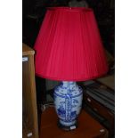A DECORATIVE BLUE AND WHITE PORCELAIN TABLE LAMP AND RED PLEATED SHADE