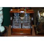 A MODERN WOODEN CASED TWIN TANTALUS, THE DECANTERS OF SQUARE FORM.