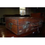 AN EARLY 20TH CENTURY LEATHER SUITCASE, BEARING SOME ORIGINAL PAPER TRAVEL LABELS