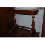 A VICTORIAN WALNUT FOLD OVER GAMES TABLE ON BALUSTER CARVED ENDS WITH FOUR DOWNSWEPT SUPPORTS, WHITE