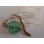 AN EMERALD TUMBLED POLISHED STONE PEBBLE MOUNTED ON PART YELLOW METAL CHAIN