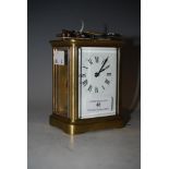 A BRASS CARRIAGE CLOCK WITH WHITE ROMAN NUMERAL DIAL