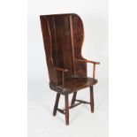 An 18th century provincial elm and oak armchair, the high panelled back with winged side panels to